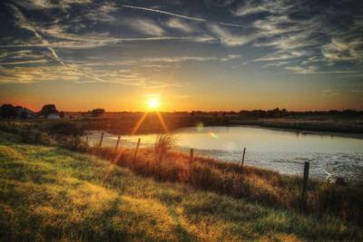 Scenic view of river against sky at sunset