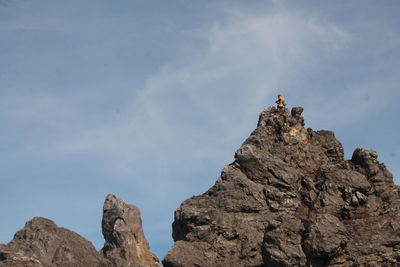 Low angle view of people on rock against sky