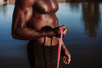 Sportsman pulling resistance band while standing against sea