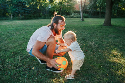 Fathers day. father playing ball with toddler baby boy outdoor. happy dad and active family life.