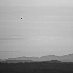 Scenic view of mountains against sky and hot air baloon