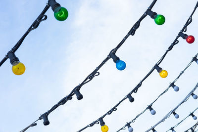 Low angle view of balloons hanging against blue sky