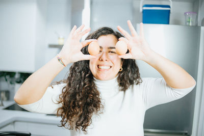 Portrait of smiling woman holding food in kitchen