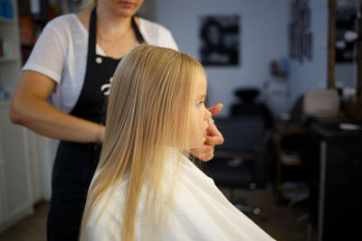 Hairdresser working on girl hair in salon