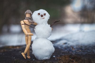 Close-up of wooden doll with snow art on field