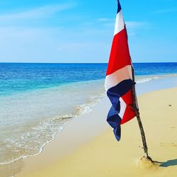 Red flag on beach against blue sky