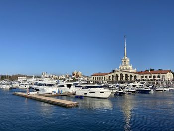 Sailboats in city against clear blue sky