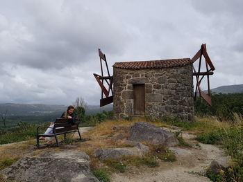 Men sitting on rock against sky