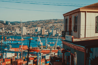 Sailboats in city by sea against sky