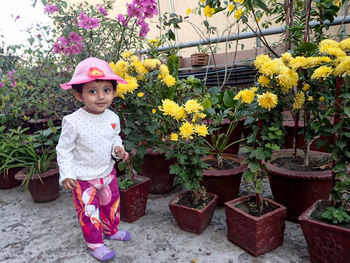 Full length of cute girl standing by flowering plants