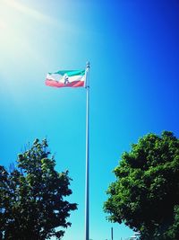 Low angle view of flag against clear blue sky