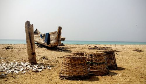 Boats moored by baskets on shore against sky