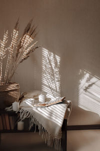 A shade from blinds on white wall and wooden table in the morning. a cup of coffee and an open book