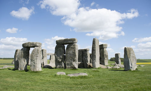 Stone structure in field against cloudy sky