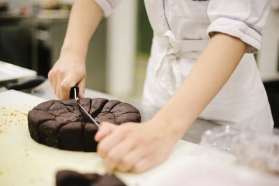 Midsection of woman cutting cake