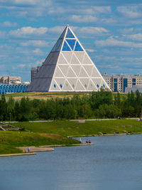 View of building by river against cloudy sky