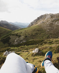 Low section of man on mountain against sky
