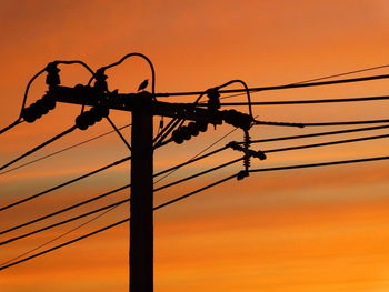 Low angle view of silhouette electricity pylon against sky during sunset