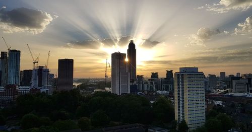 Modern buildings in city against sky during sunset