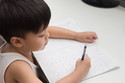 Close-up of boy writing in book at table