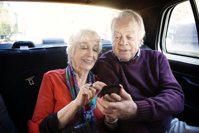 Senior couple using smart phone in car