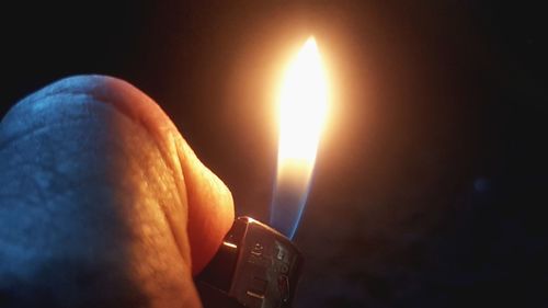 Close-up of hand holding burning candle