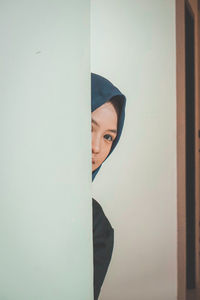 Portrait of young man hiding behind curtain