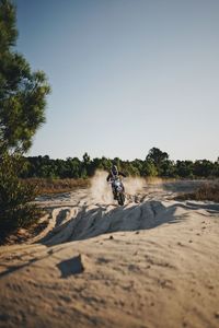 People riding motorcycle on road against clear sky