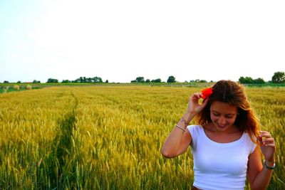 Young woman standing on field against sky