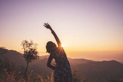 Woman standing on field against sky during sunset