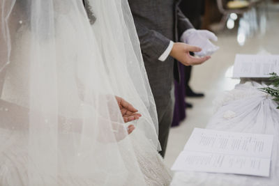 Midsection of heterosexual couple reading vows in wedding hall