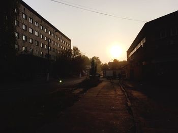 Empty road along buildings at sunset