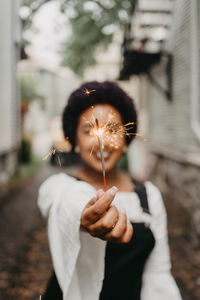 Portrait of smiling woman holding illuminated sparkler