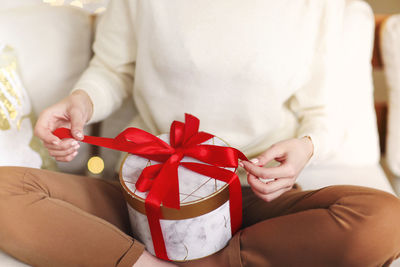 Midsection of woman holding red in box