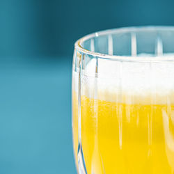 Close-up of beer glass against blue background