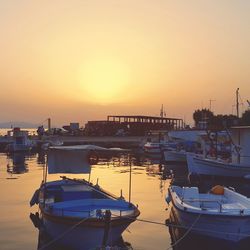 Boats moored at harbor against clear sky during sunset