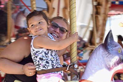 Portrait of smiling girl with carousel in amusement park