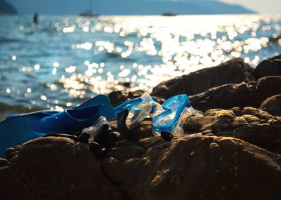 Diving equipment on rocks at beach during sunset