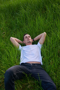 Full length of young woman sitting on grassy field