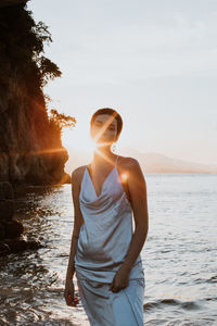 Young woman standing by sea against sky during brazilian sunset.