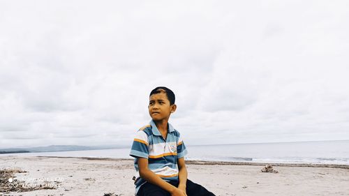 Boy on beach against sky