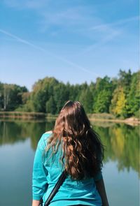 Rear view of woman looking at lake against sky