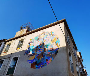 Low angle view of clothes drying on building against clear blue sky