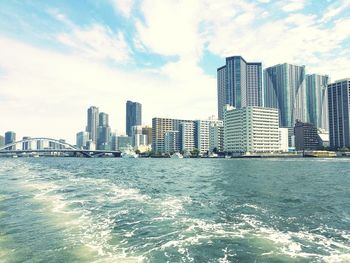 Sea by cityscape against sky