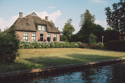 Exterior of house by garden and pond against sky