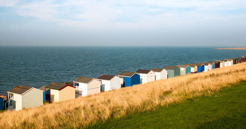 Beach huts by sea against sky