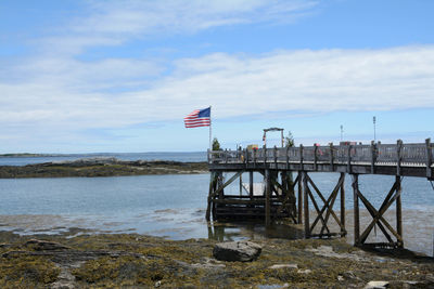 American flag mounted at the end of the pier at low tide