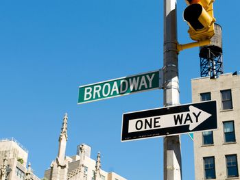 Low angle view of road sign against clear blue sky