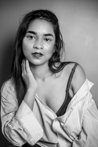 Portrait of young woman standing against white background