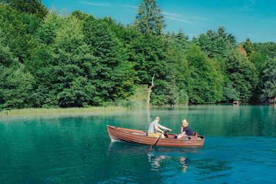 People in boat on lake against trees